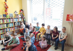 Dzieci słuchają opowiadania czytanego przez bibliotekarkę